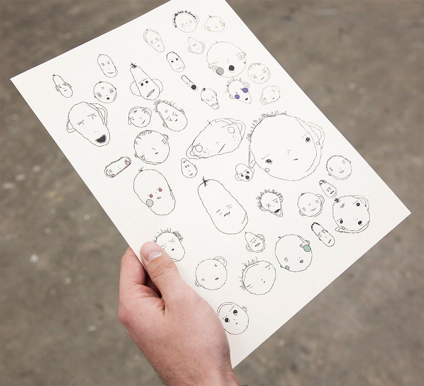 There are a variety of weird faces on a printed sheet of paper/ Some are large baby-like faces, while others are small. All are outlined in black and very few have any color. They seem to be mostly circular or oblong shape faces. Some have blush, freckles
