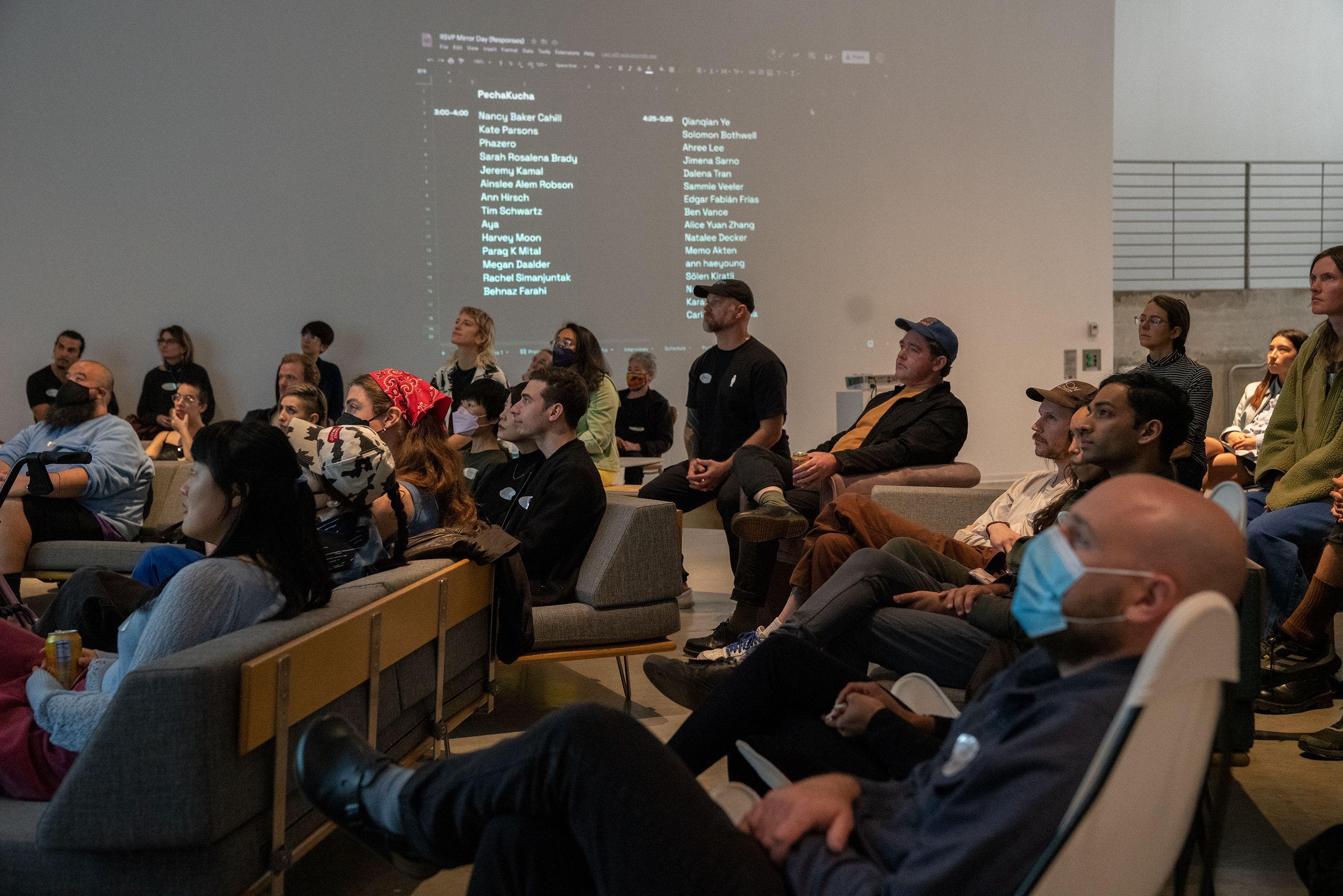 a group of people sit in a presentation space 