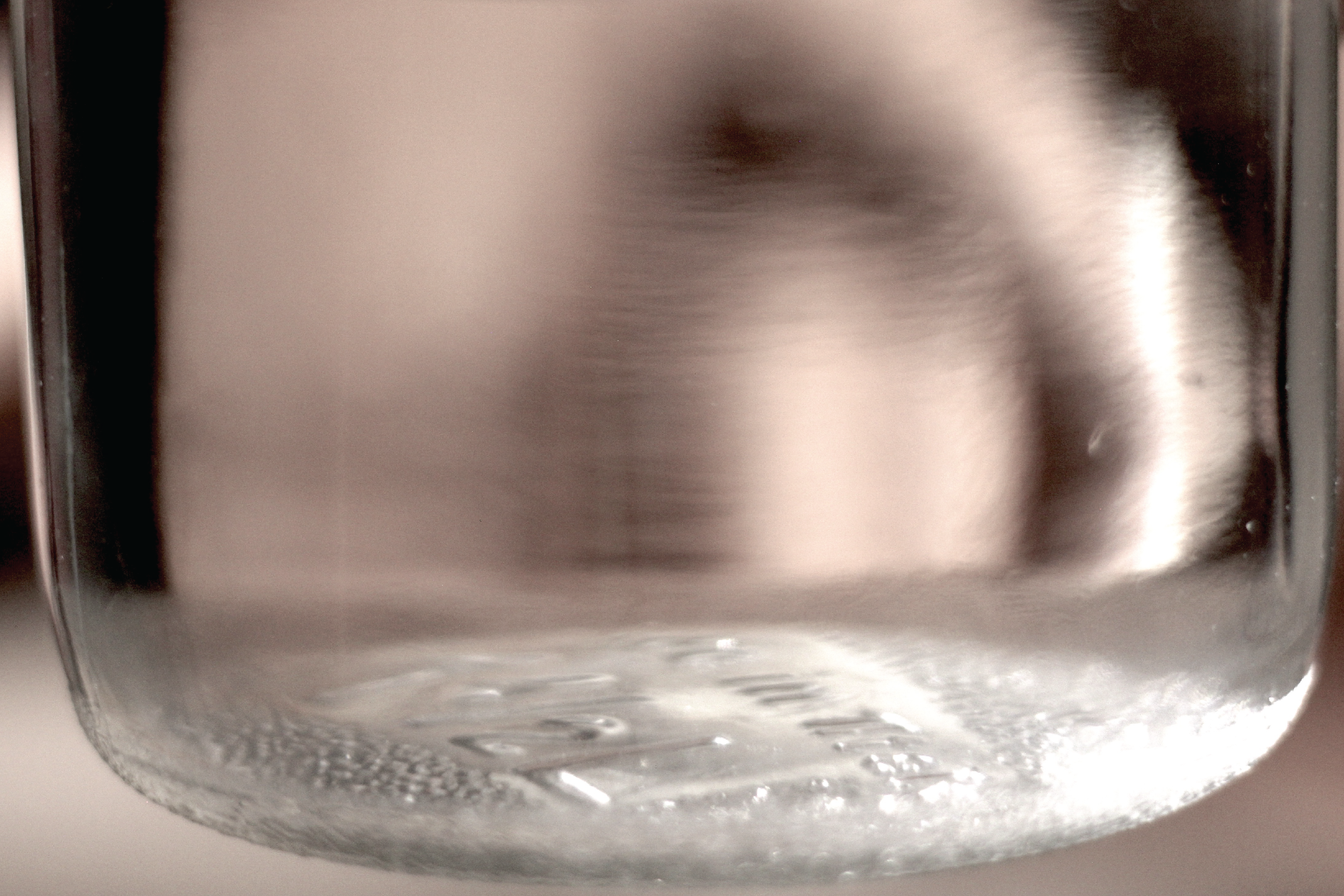A close-up of a glass jar filled with clear liquid.